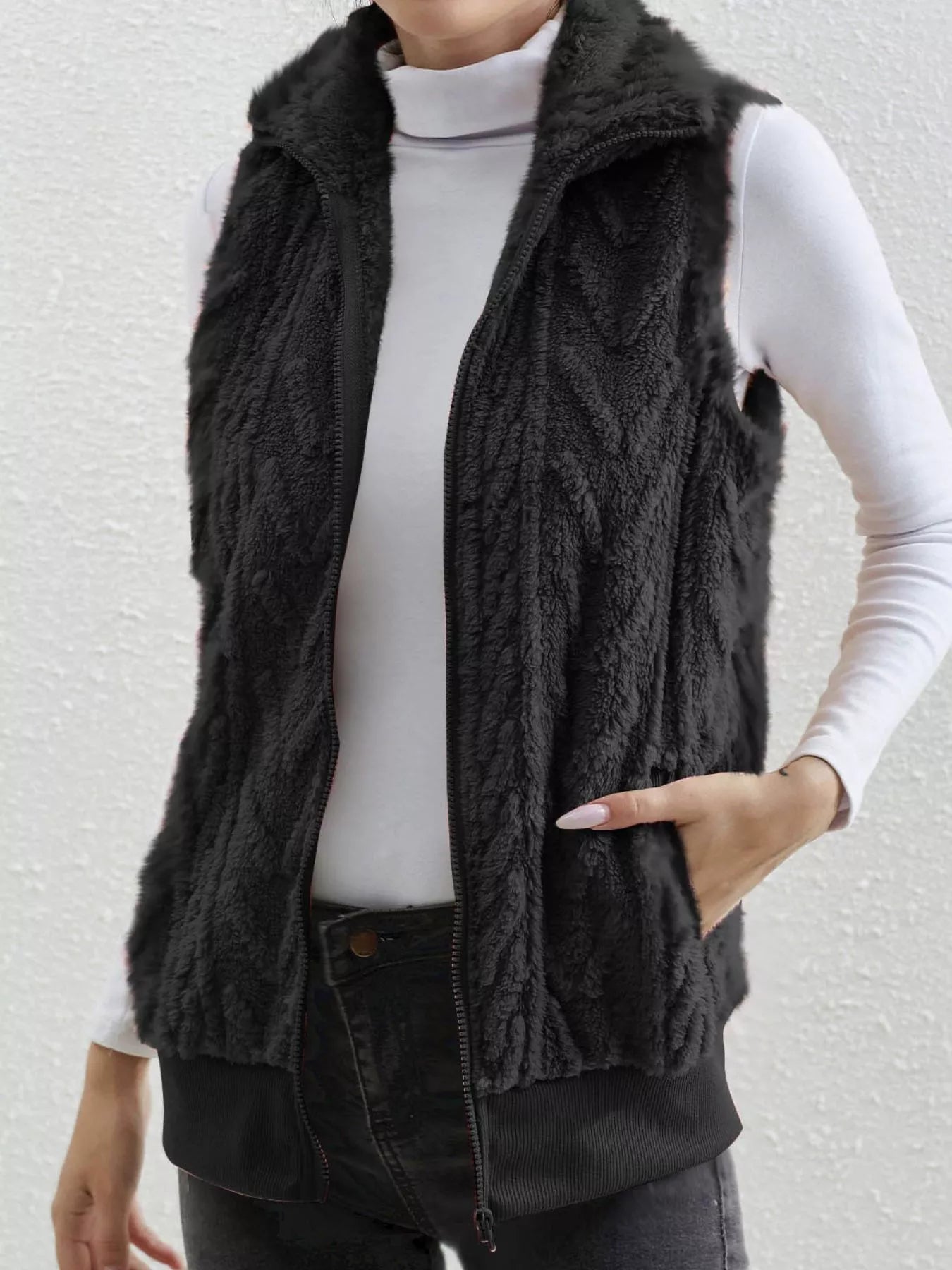Black faux fur zip-up vest with chevron pattern and pockets.