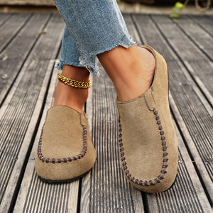 Beige slip-on flats with round toe and contrast stitching detail.