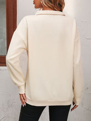 Cream quarter-zip relaxed fit sweatshirt with long sleeves and a collared neckline.