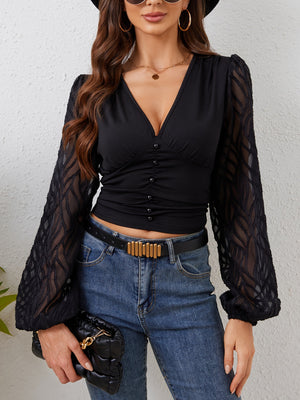 Black ruched V-neck blouse with sheer patterned puff sleeves and button front detail.