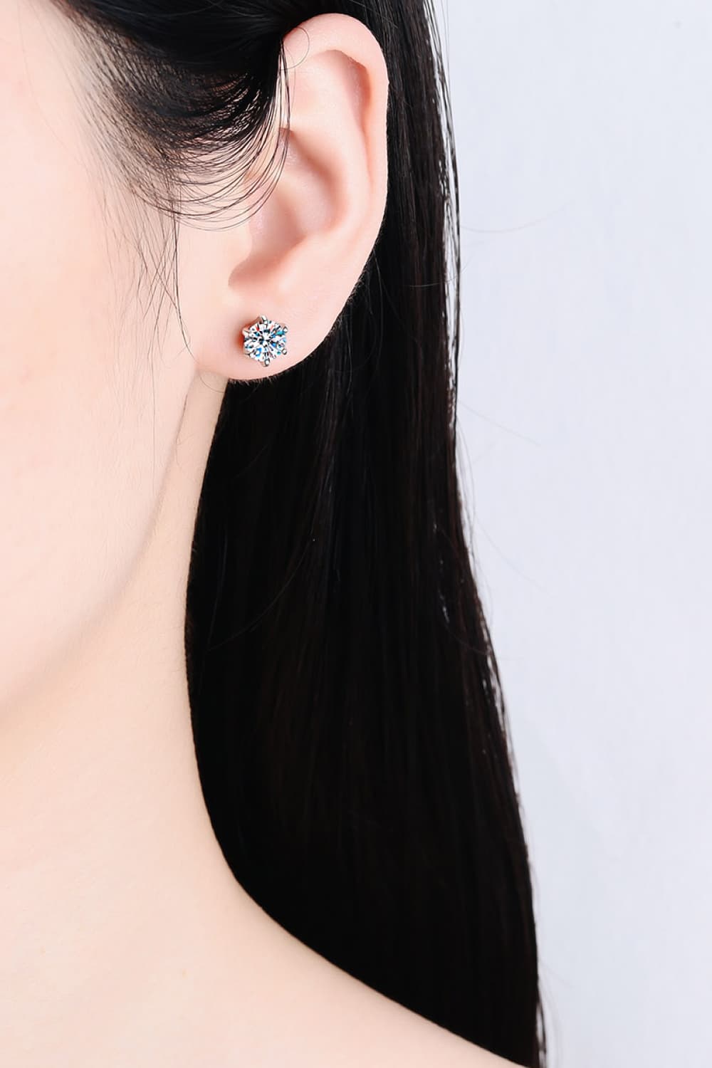 Silver six-prong solitaire stud earrings with a sparkling blue center stone.