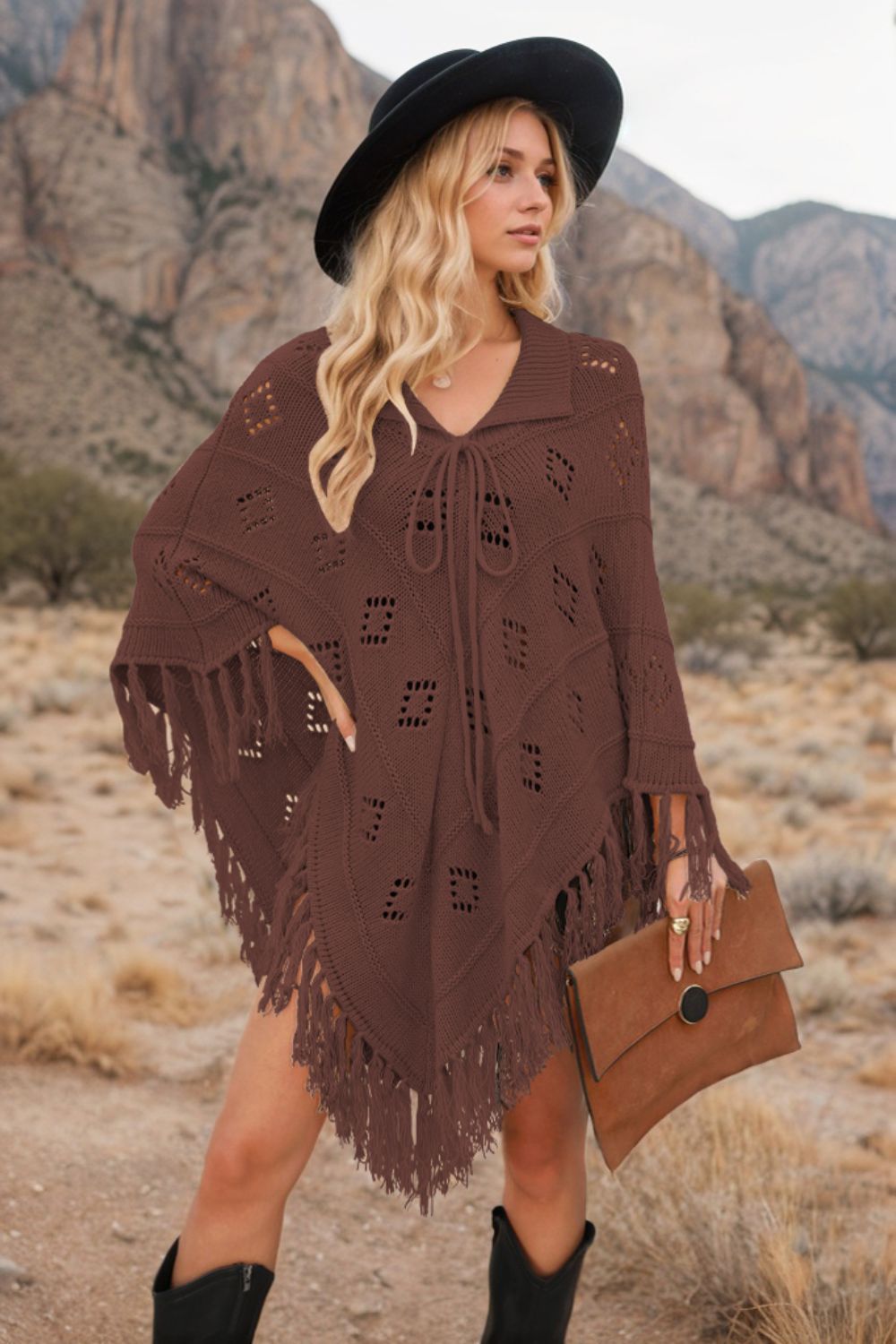 Brown knit poncho with geometric cutouts and fringe, featuring a tie-neck and collar.
