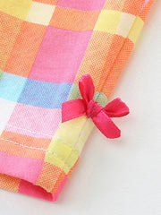 Toddler outfit detail: pink plaid cotton fabric with a small pink bow accent.