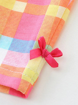 Toddler outfit detail: pink plaid cotton fabric with a small pink bow accent.