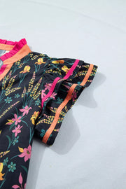 Black cotton blouse with vibrant floral print, contrast trim, and ruffled neckline.
