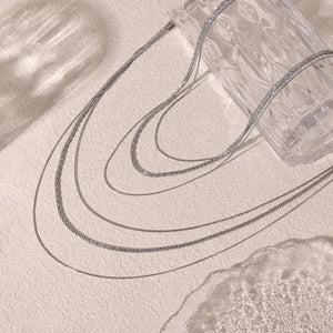 Delicate three-strand silver crystal necklace with layered chains.