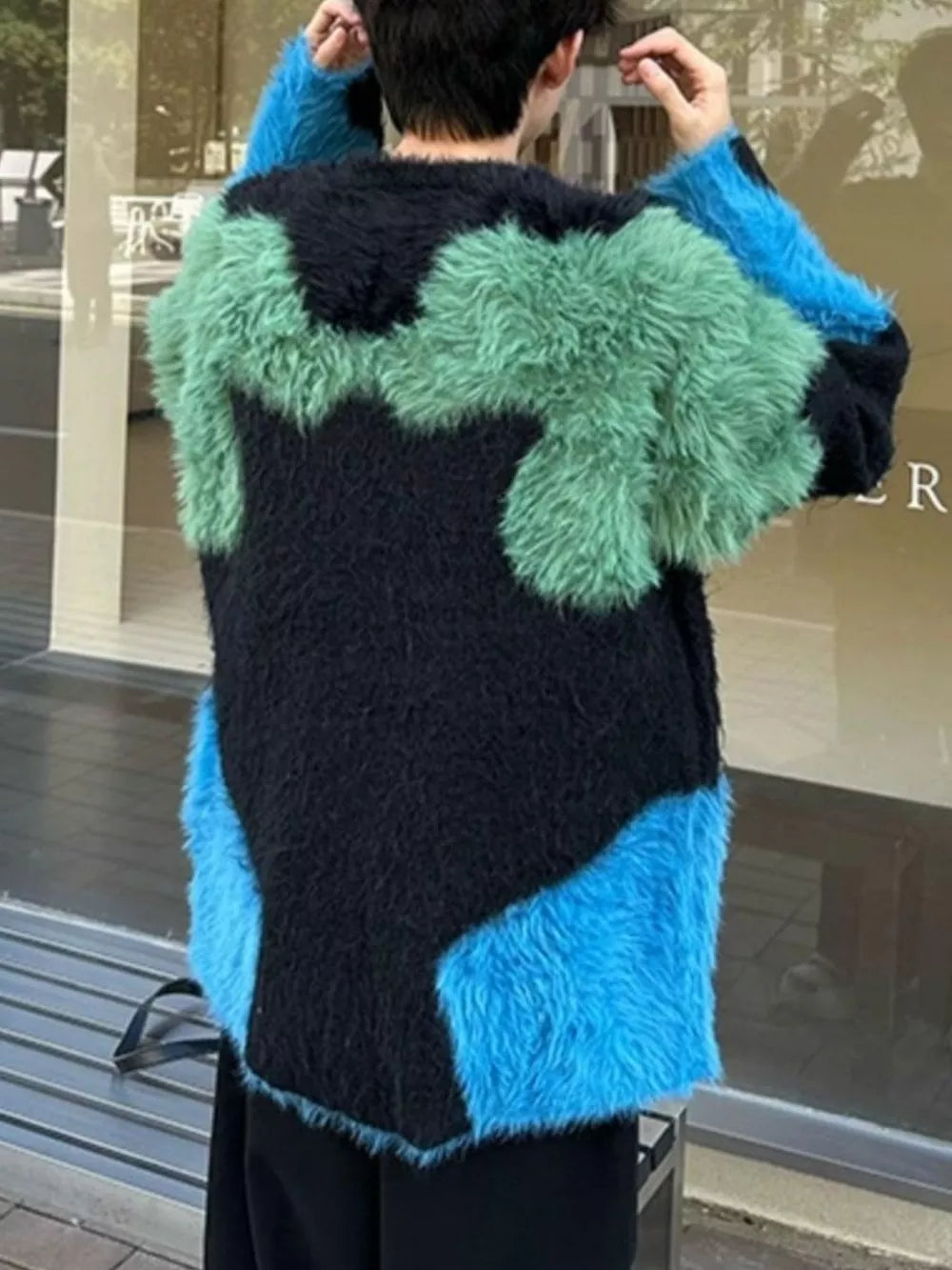 Oversized knit sweater with black, green, and blue color block pattern and fuzzy texture.