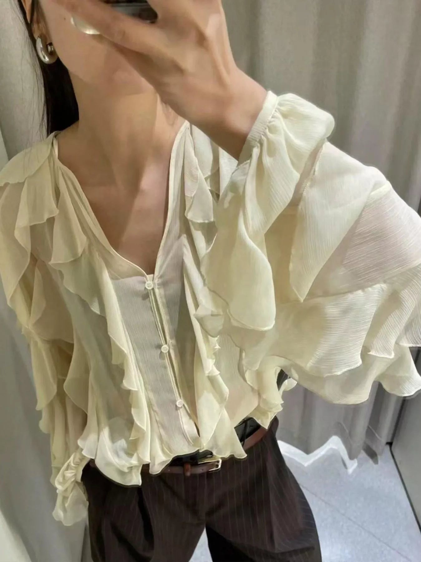 Sheer beige ruffled long-sleeve blouse with V-neck and button front.