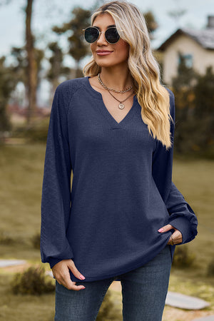 Dark blue waffle knit raglan v-neck top with textured sleeves.