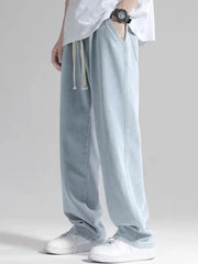 Men's light blue loose fit jeans with drawstring waist and pockets.