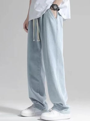 Men's light blue loose fit jeans with drawstring waist and pockets.