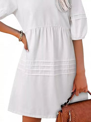 White denim mini dress with puff sleeves, tiered skirt, and smocked waist.
