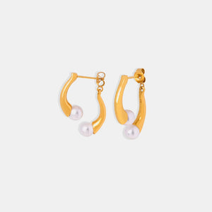 Gold sculptural pearl drop hoop earrings with a modern curved design.