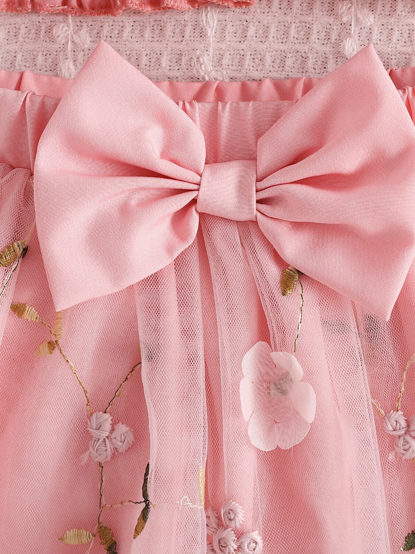 Pink smocked off-shoulder top and tulle skirt set with floral embroidery and bow detail.