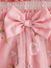 Pink smocked off-shoulder top and tulle skirt set with floral embroidery and bow detail.