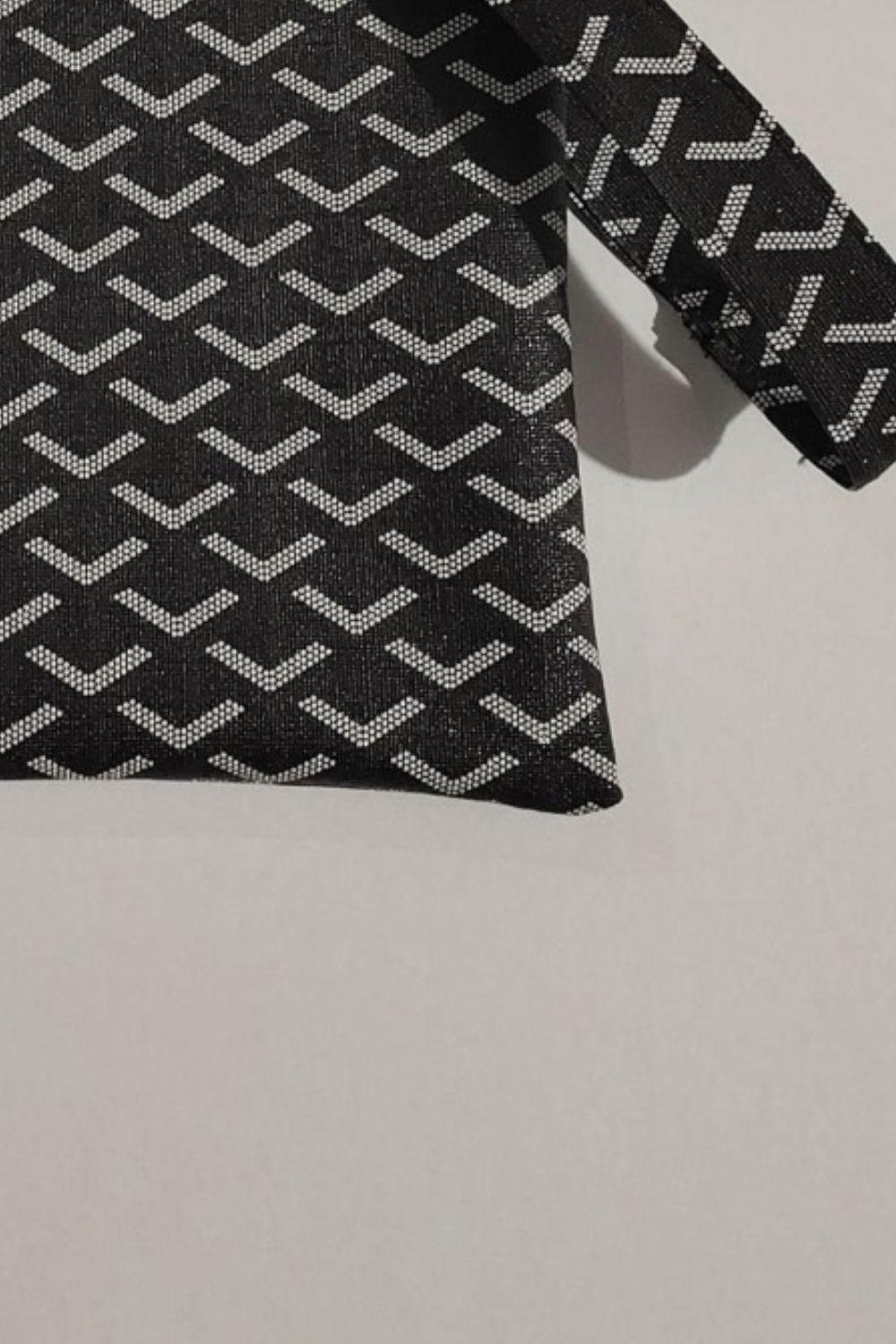 Black clutch bag with geometric pattern and wrist strap detail