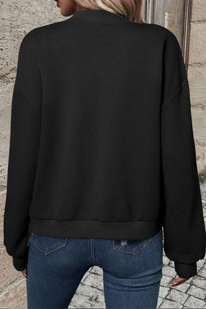Black quilted bomber jacket with textured diamond pattern and ribbed cuffs.