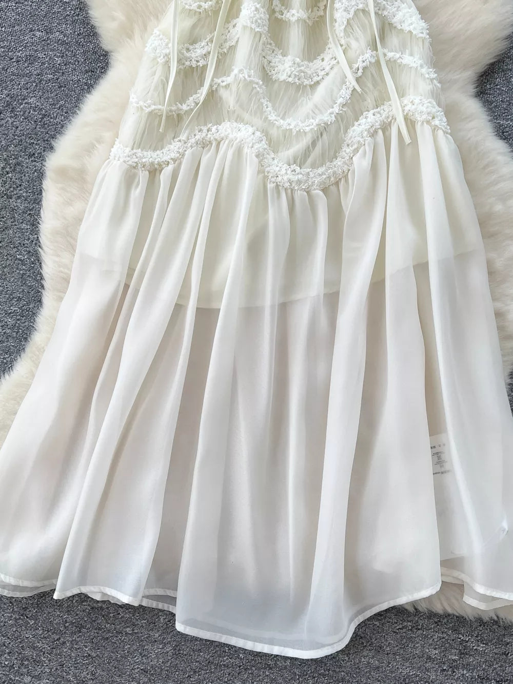 White tiered lace midi maternity dress with bow detail and sheer skirt.