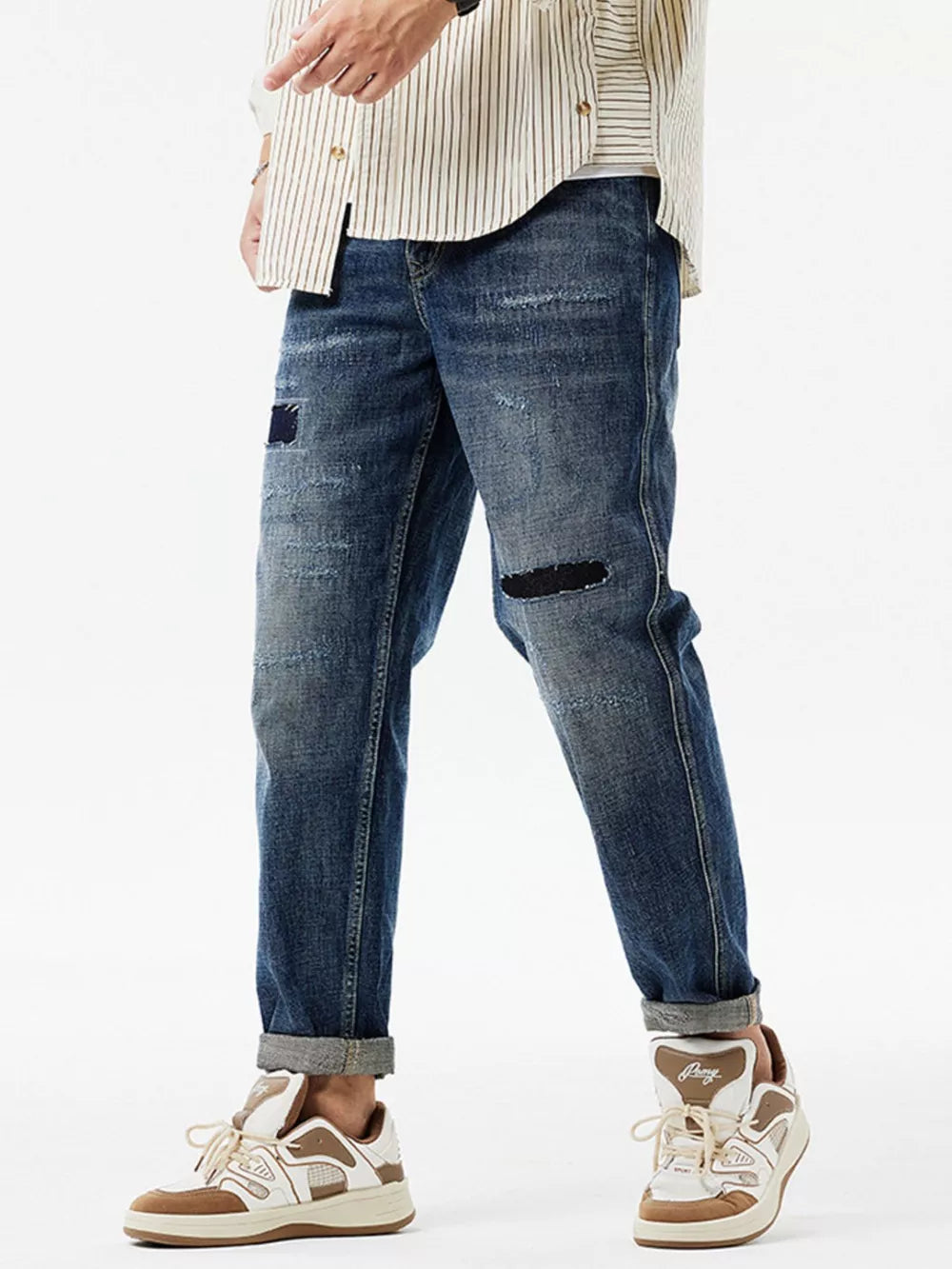 Men's dark blue distressed cotton jeans with patchwork and cuffed hems.
