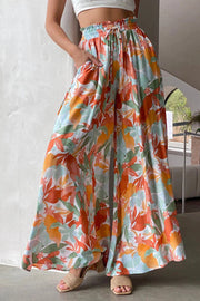 Botanical print palazzo trousers with a drawstring waist and wide legs in orange, aqua, and green.