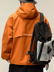 Orange hooded windbreaker jacket with white text detail on back, worn with a backpack.