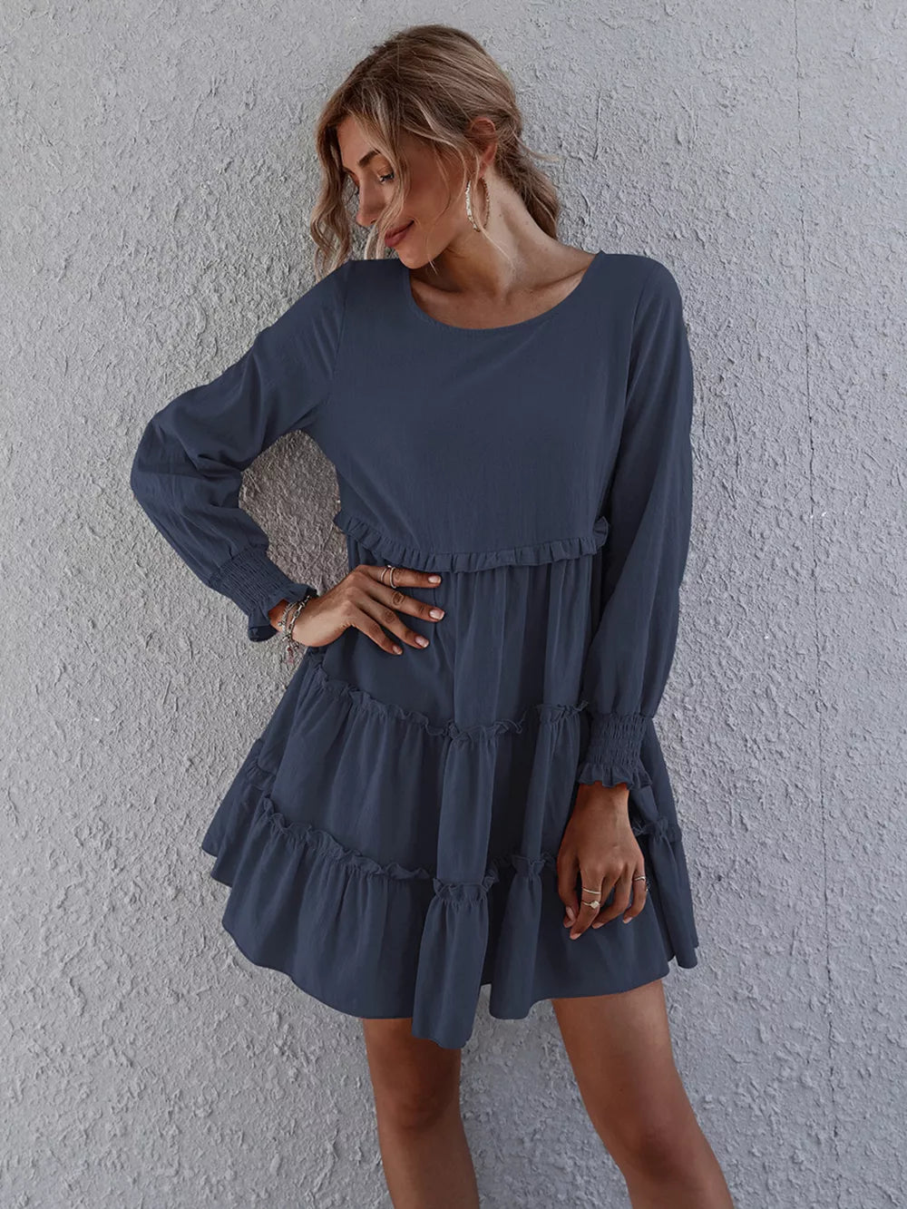 Navy blue tiered mini dress with long sleeves and ruffled details.