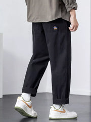 Black cotton wide-leg trousers with cuffed hems and embroidered pocket detail.