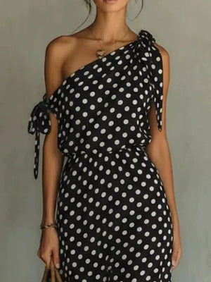 Black polka dot one-shoulder maxi dress with cinched waist and tie details.