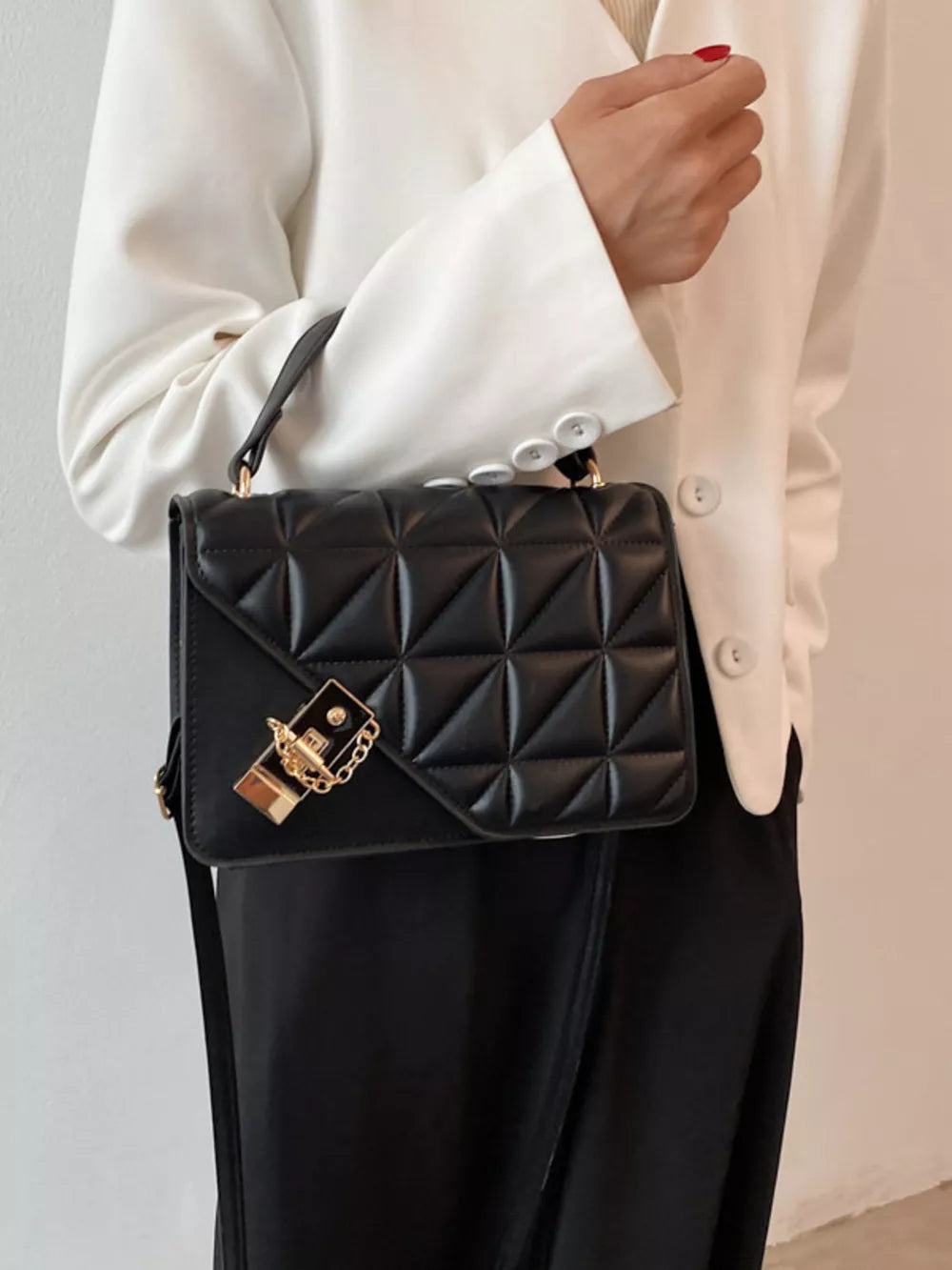 Black diamond quilted PU leather crossbody bag with gold hardware and chain detail.