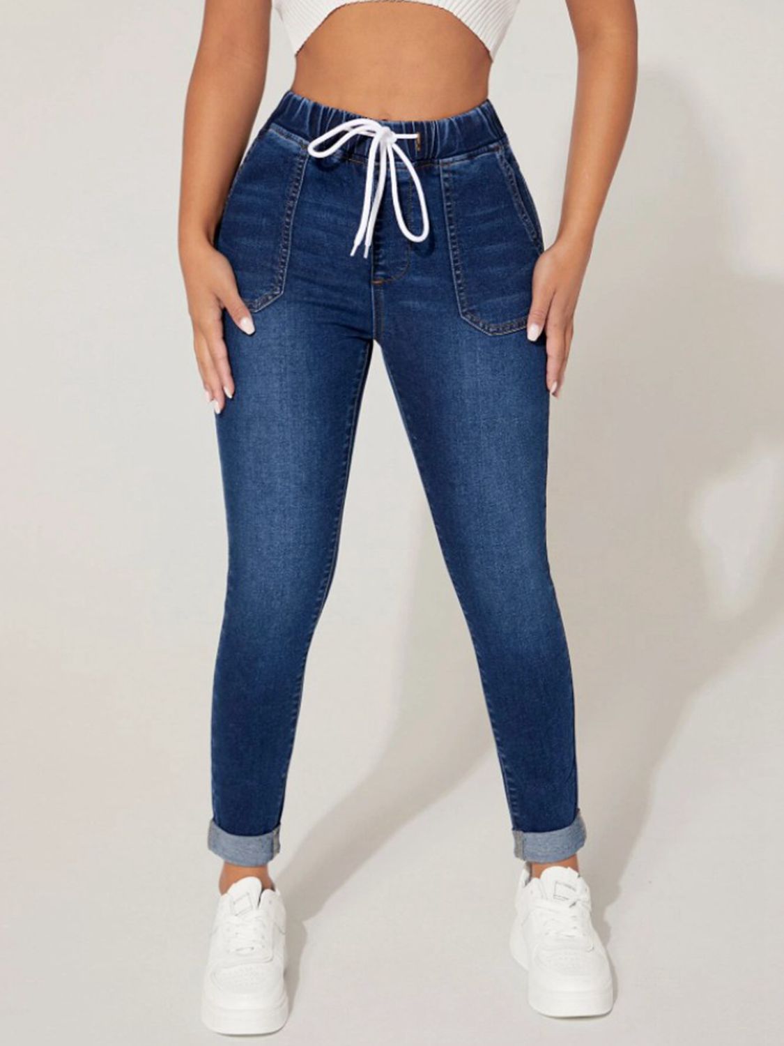 Medium wash denim joggers with a white drawcord waist and cuffed hems.