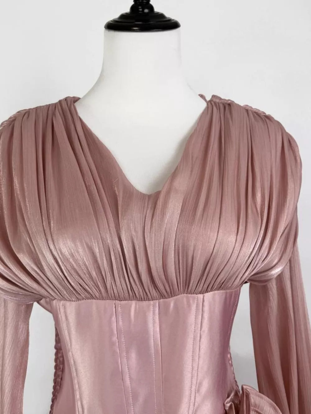 Pink ruffled mini dress with corset waist and long sleeves.