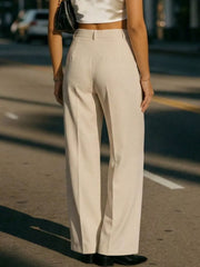 Cream high-waisted pleated trousers with a wide leg, shown from the back.