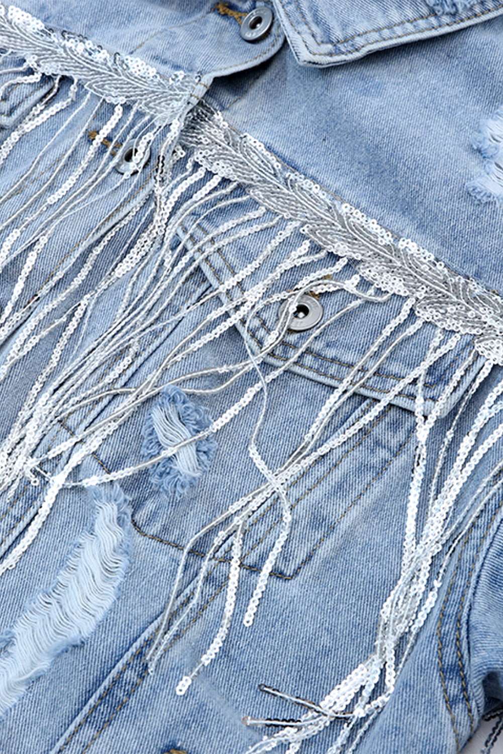 Medium wash denim trucker jacket with sequin fringe and distressed details.