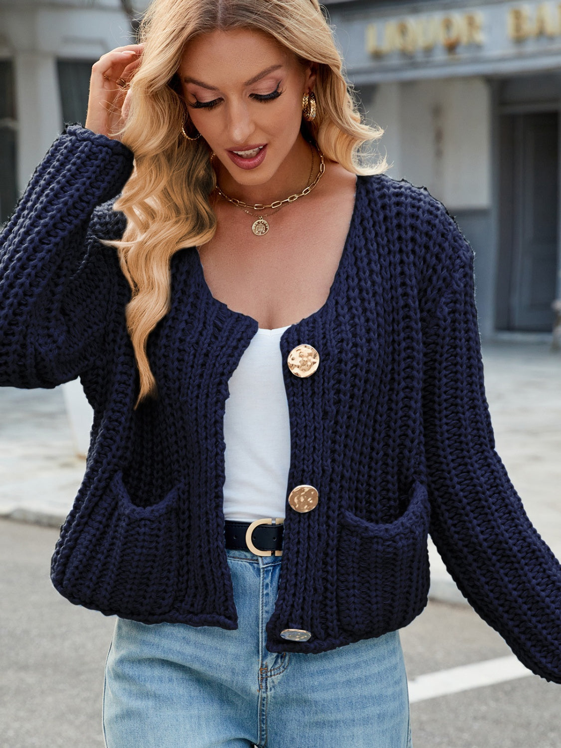 Chunky knit dark blue cardigan with gold buttons and patch pockets.