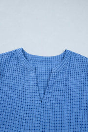 Blue checkered midi dress with notched neckline and textured fabric.