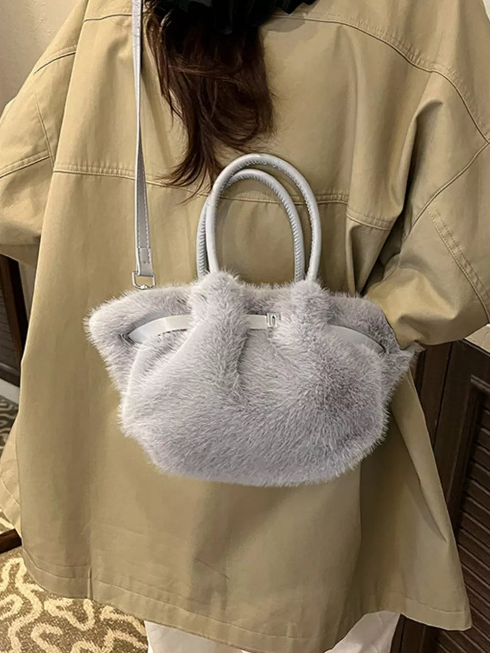 Plush crossbody bag in gray with chic buckle detail and top handles.