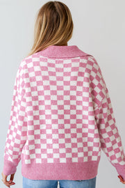 Pink checkerboard knit polo sweater with a collared neckline.