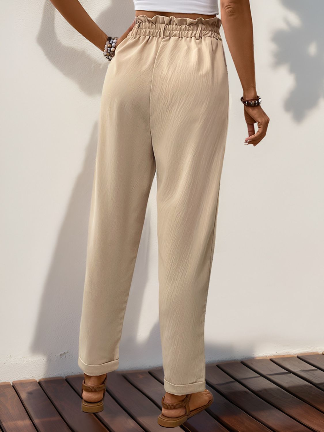 Tan linen blend trousers with gathered waistline and cuffed hems.