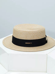 Elegant straw boater hat in beige with a black ribbon band and gold accent
