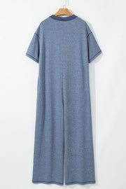 Denim-trimmed wide-leg utility jumpsuit in dusty blue with short sleeves and a collar.