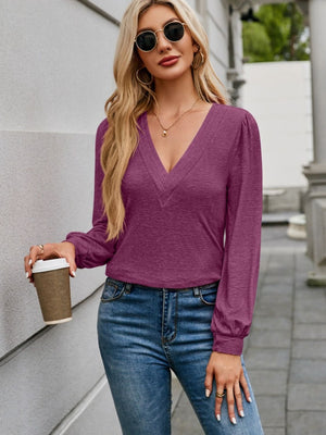 Plunge neckline gathered sleeve top in deep purple with textured detail at neckline.