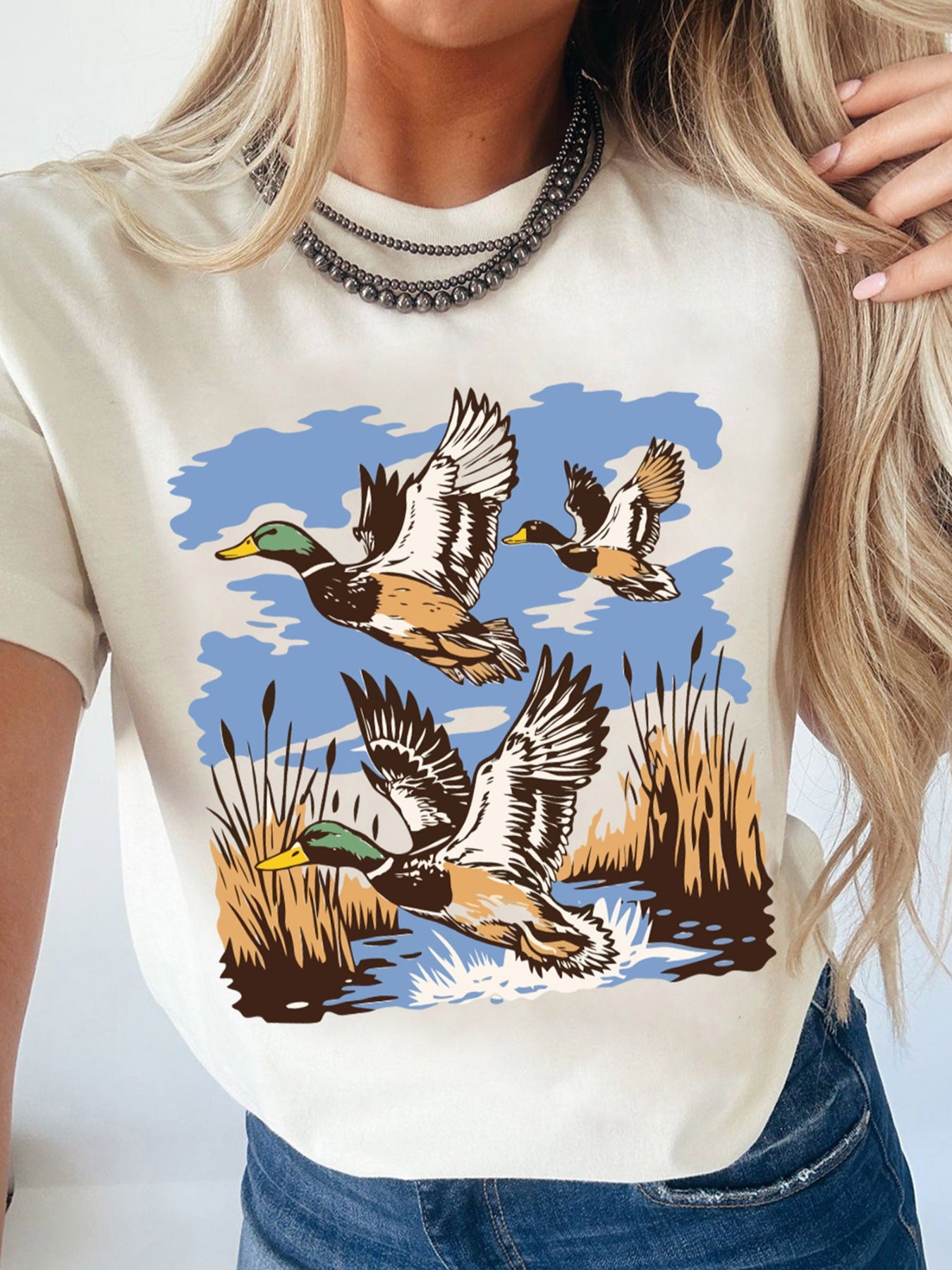 Cream cotton t-shirt with a graphic of three mallard ducks flying over reeds and water.