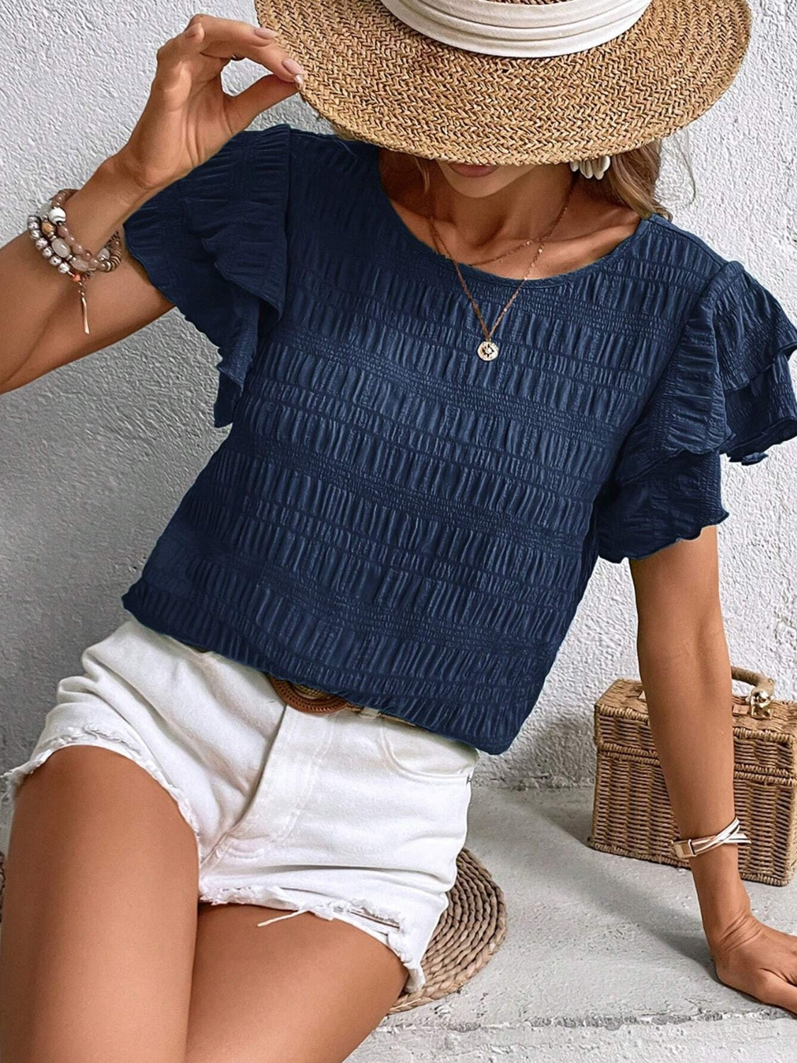 Dark blue textured smocked blouse with ruffle sleeves.