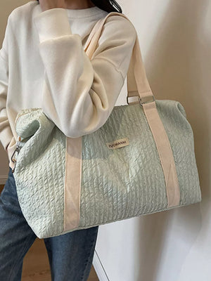 Textured travel bag in light green with cream straps and a detachable pouch.