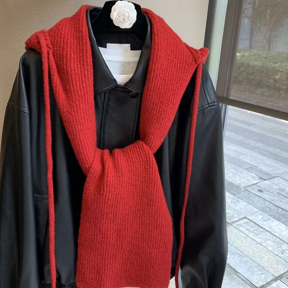 Red hooded knit tie scarf with ties, worn over a black jacket.