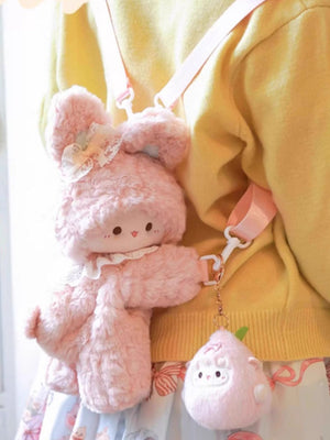 Pink plush bunny backpack with lace collar and bow, attached to a yellow sweater.