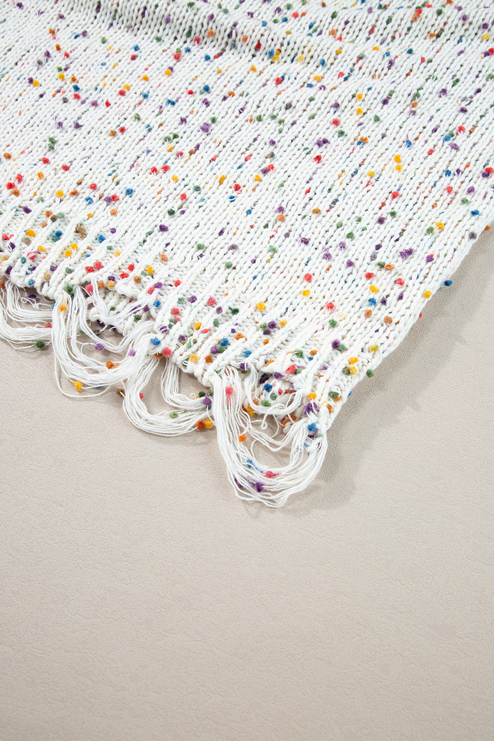White confetti knit sweater with colorful flecks and distressed fringe hem.