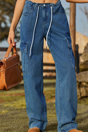 Medium wash denim cargo pants with drawstring waist and utility pockets.