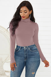 Sculpted turtleneck bodysuit in dusty pink with long sleeves, paired with jeans.