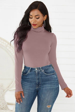 Sculpted turtleneck bodysuit in dusty pink with long sleeves, paired with jeans.